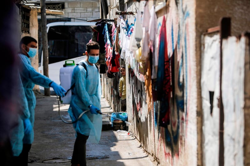Palestinian volunteers sprays disinfectant a street at Al Shati refugee camp in Gaza City . AFP
