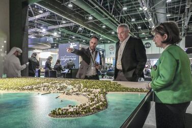A sales representative guides a Cityscape attendee over the IMKAN model in Abu Dhabi. Victor Besa / The National