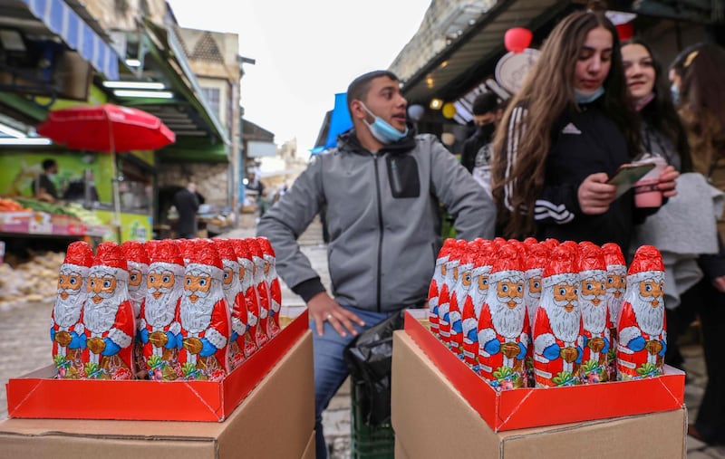 A street vendor selling Santa Claus wrapped chocolate calls for customers at a market in the Old City of Jerusalem. AFP
