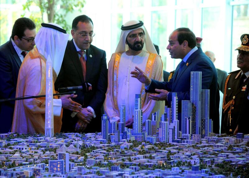 A handout picture made available on March 14, 2015 by the Egyptian presidency shows Egyptian President Abdel Fattah al-Sisi (R) and Prime Minister of the United Arab Emirates (UAE) and ruler of Dubai Sheikh Mohammed bin Rashid al-Maktoum (C) listening to Egyptian investment minister Ashraf Salman (3rdR) as they look at a scale model of the new Egyptian capital Cairo displayed at the congress hall in the Red Sea resort of Sharm el-Sheikh. (Photo by MOHAMED SAMAAHA / EGYPTIAN PRESIDENCY / AFP)