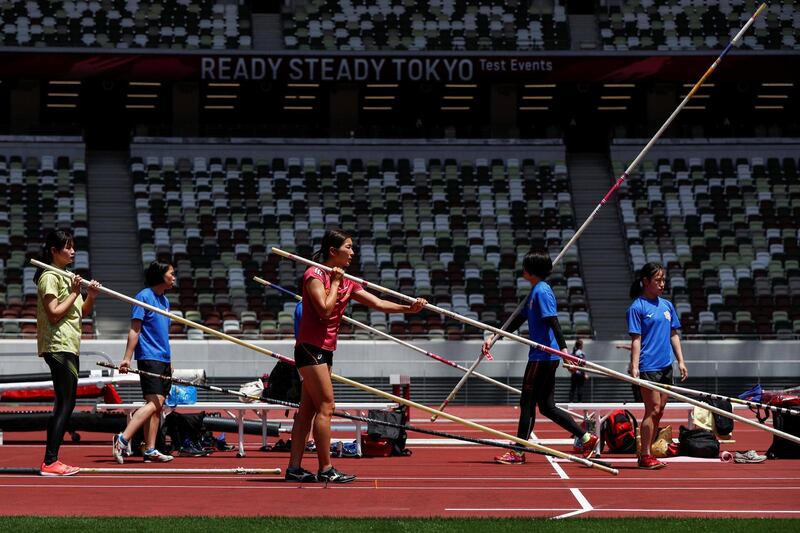 Athletes are seen with pole vaults before competing in their event at the morning session of the Athletics test event at Tokyo's Olympic Stadium. Reuters