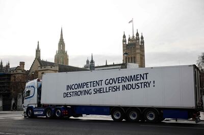 A truck drives past the Houses of Parliament with a message that reads "Incompentent government destroying shellfish industry" in a protest action by fishermen against post-Brexit red tape and coronavirus restrictions, which they say could threaten the future of the industry, in London on January 18, 2021. / AFP / Tolga Akmen
