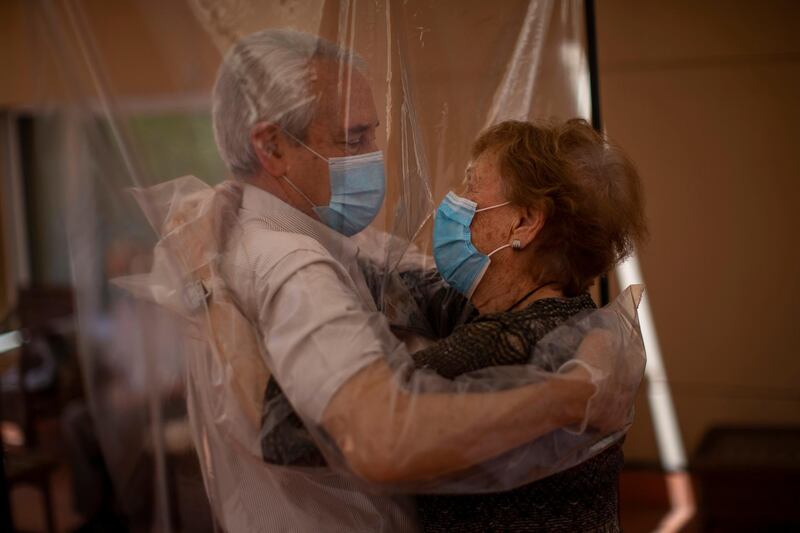 Isabel Pérez López, 96, receives an embrace through a plastic film screen from her visiting son-in-law Jose Maria Vila, 69, at a nursing home in Barcelona, Spain. AP