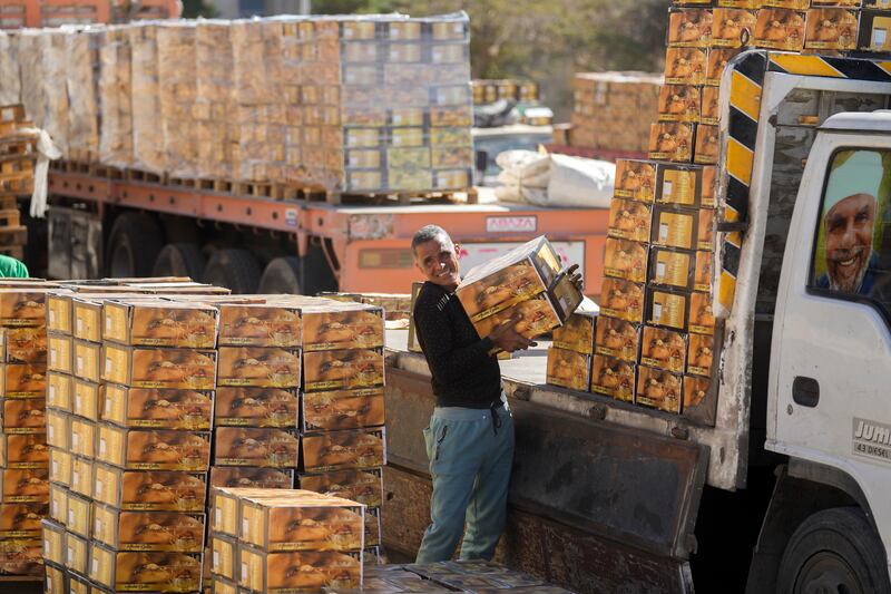 A worker of the Egyptian Food Bank NGO loads donated boxes of dates on to a truck headed for Gaza at a warehouse in New Cairo, Egypt. AP