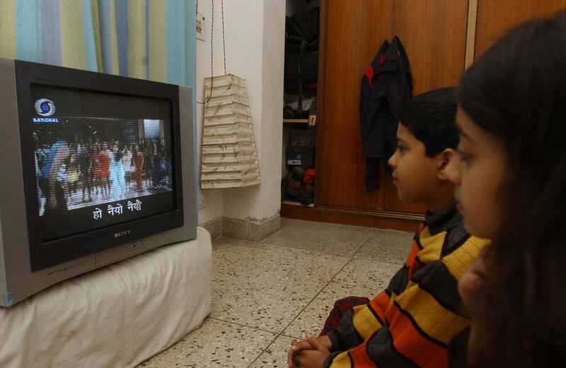 In this picture taken 22 January 2006, Indian children watch 'Rangoli' a Hindi film on television with subtitles in New Delhi.  Indian film producer Brij Kothari Kothari has assisted thousands of Indians helping them to learn their mother tongues and foreign languages by watching popular films with subtitles. AFP PHOTO/Manpreet ROMANA (Photo by MANPREET ROMANA / AFP)