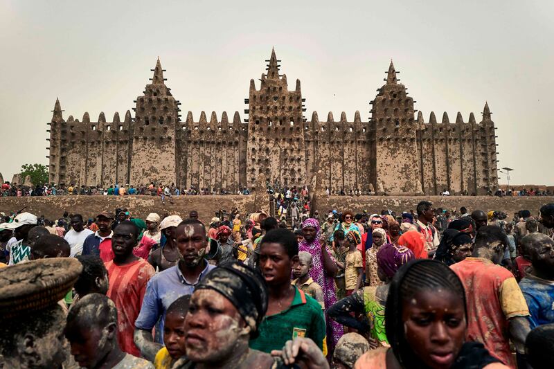 People take part in the annual rendering of the Great Mosque of Djenne in central Mali on April 28, 2019.
 Several thousand residents of the historic central Malian city of Djenne, a UNESCO World Heritage site, took part in the annual rendering ceremony of the Grand Mosque, which will now be powered by solar electricity. The rendering of the building with banco (a mixture of soil and water, with rice bran, shea butter and baobab powder) made by the city's inhabitants, helps to protect the mosque from bad weather ahead of the rainy season. / AFP / MICHELE CATTANI
