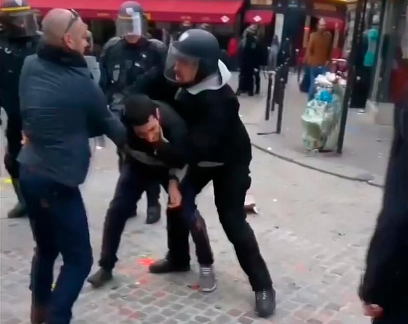 In this image taken from video, a man identified as Alexandre Benalla, right, a security chief to French President Emmanuel Macron, confronting a student during a May Day demonstration in Paris, May 1, 2018.  The video came to light Thursday July 19, 2018, showing one of Macron's security chiefs beating a student demonstrator, until now cloaked in secrecy, and is drawing a fierce public backlash over what is seen as mild punishment of a two-week suspension, and a possible cover-up. (Nicolas Lescaut via AP)