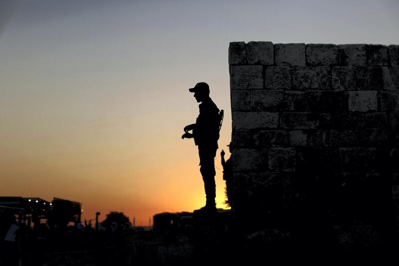 In this Saturday, July 27, 2019 photo, a Syrian soldier is silhouetted against the setting sun as he stands guard at the main gate of the ancient Aleppo Citadel in Aleppo, Syria. Rebels still frequently strike with shelling and mortars into Aleppo, killing civilians nearly three years after the government recaptured the city. Aleppo is a symbol of how President Bashar Assad succeeded in turning the tide in Syria‚Äôs long civil war with a series of wins, but it‚Äôs equally a symbol of how he‚Äôs been unable to secure a final victory. Half of Aleppo remains in ruins, and rebels remain on the doorstep. (AP Photo/Hassan Ammar)