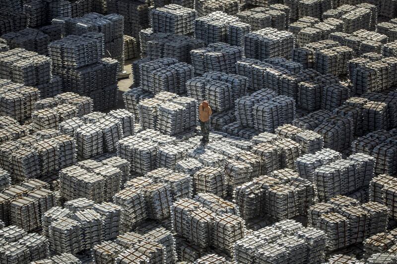 A worker stands on bundles of aluminum ingots at a China National Materials Storage and Transportation Corp. stockyard in Wuxi, China, on Thursday, Aug. 23, 2018. The U.S. and China imposed fresh tariffs on each other's goods in the middle of trade talks aimed at averting the worsening conflict between the world's two biggest economies. Photographer: Qilai Shen/Bloomberg