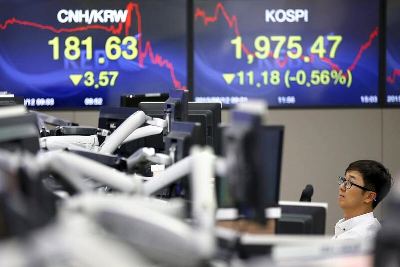 A currency dealer works in front of electronic boards showing the Korea Composite Stock Price Index and the exchange rate between the Chinese yuan and South Korean won, at a dealing room of a bank in Seoul, South Korea, on August 12, 2015. Kim Hong-Ji / Reuters
