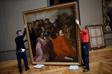 Workers handle the painting called 'The Healing of Saint Bonaventure as a Child by Saint Francis' by Spanish painter Francisco de Herrera, in the Louvre museum, in Paris, Tuesday, Feb. 9, 2021. The forced closure has granted museum officials a golden opportunity to carry out long-overdue refurbishments that were simply not possible with nearly 10 million visitors a year. (AP Photo/Thibault Camus)