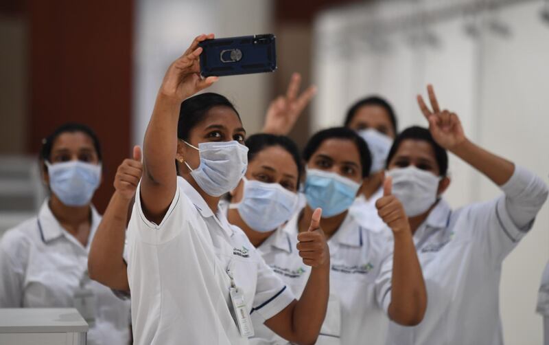 Nursing staff flash victory signs for a selfie, as they set up a huge field hospital at Dubai World Trade Centre. The facility's huge halls, typically used for exhibitions and conferences, can hold up to 3,000 beds. All photos by Karim Sahib / AFP