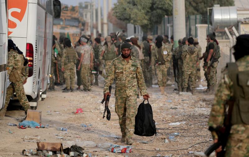 A Turkey-backed Syrian rebel fighter walks as he holds a bag and a weapon in the border town of Akcakale in Sanliurfa province, Turkey. Reuters