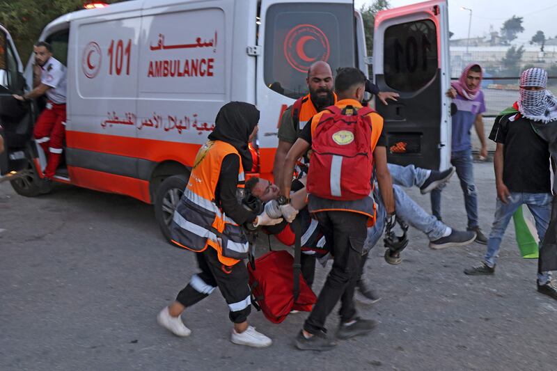 Paramedics carry a man towards an ambulance amidst clashes between Palestinian protesters and Israeli forces following a protest to denounce the annual nationalist "flag march" through Jerusalem, near the Beit El settlement at the northern entrance to the city of Ramallah in the occupied West Bank on May 29, 2022.  AFP
