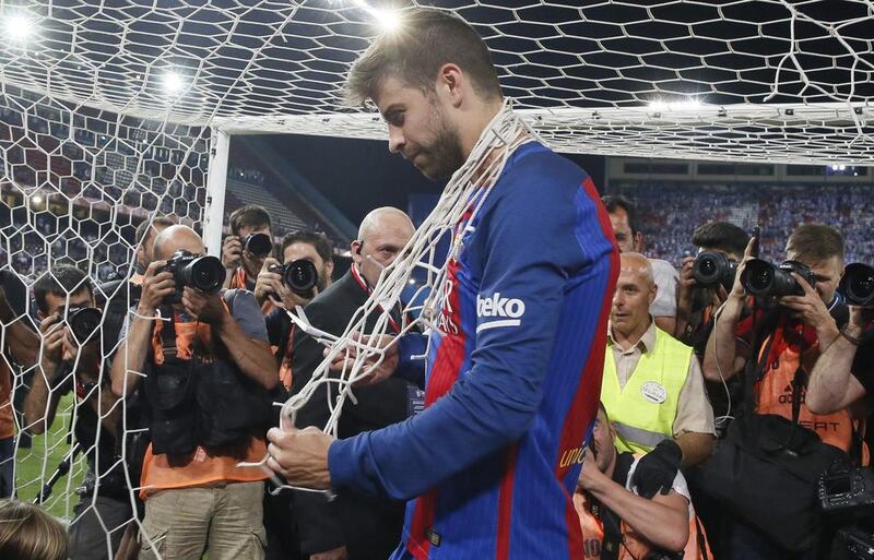 Barcelona defender Gerard Pique cuts the goal net after his club beat Deportivo Alaves to win the Copa Del Rey in Madrid. Mariscal / EPA