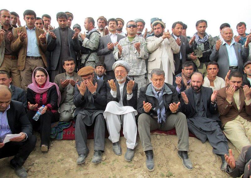 Karim Khalili, Afghan vice president, and Bismillah Mohammadi, the Afghan defence minister, pray for the victims of landslide.