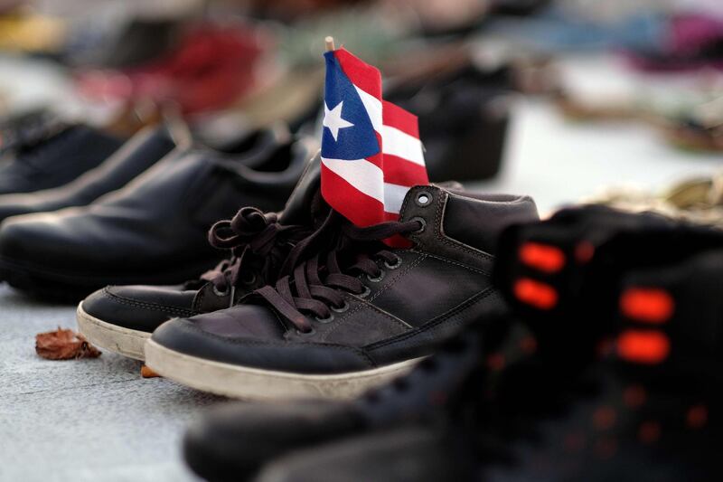 View of a Puerto Rican flag placed on a pair of shoes among hundreds displayed in memory of those killed by Hurricane Maria in front of the Puerto Rican Capitol, in San Juan.  Ricardo Arduengo / AFP