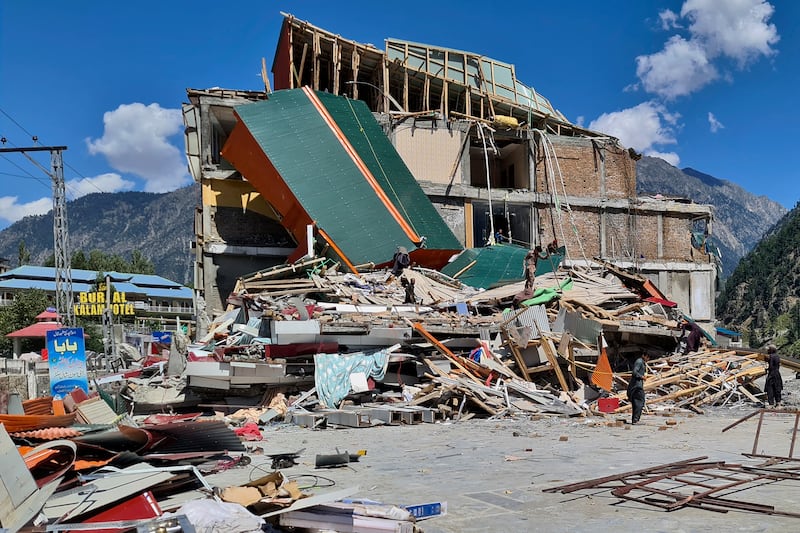 People salvage items from a damaged building in Kalam, Swat Valley. AP