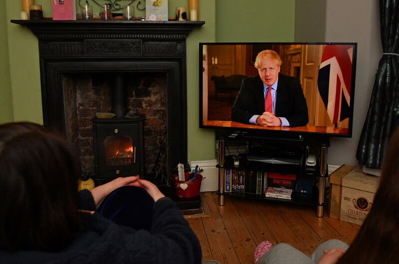 Members of a family listen as BMr ris Johnson makes a televised address to the nation from 10 Downing Street in March 2020, where he outlined the latest instructions to stay at home to help contain the Covid-19 outbreak. AFP