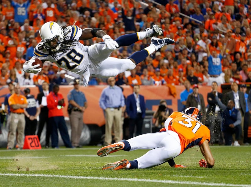 Los Angeles Chargers' Melvin Gordon dives over Denver Broncos player Justin Simmons for a touchdown during the first half of an NFL football game in Denver. Jack Dempsey / AP Photo