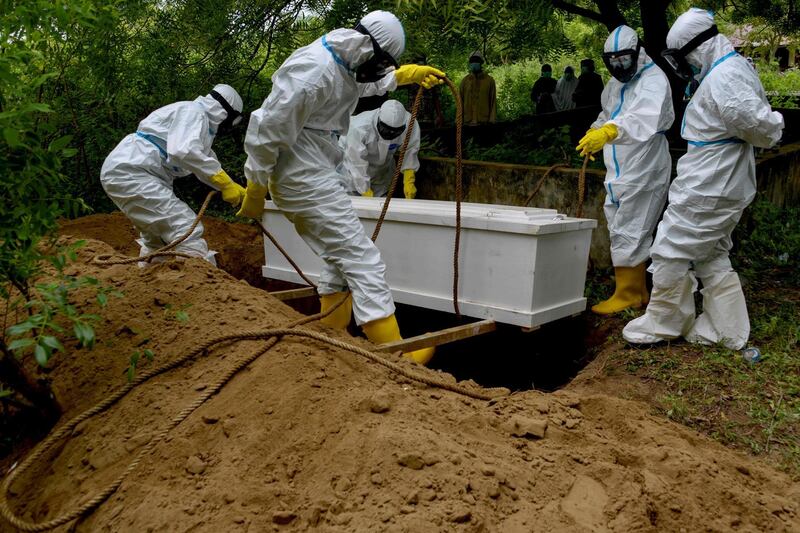 Gravediggers lower a coffin during a funeral for a Covid-19 coronavirus victim at a cemetery in Kajhu, Aceh province. AFP