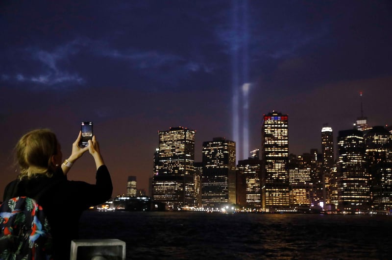 A woman records the Tribute in Light installation with her mobile phone as its illuminated over lower Manhattan. Reuters