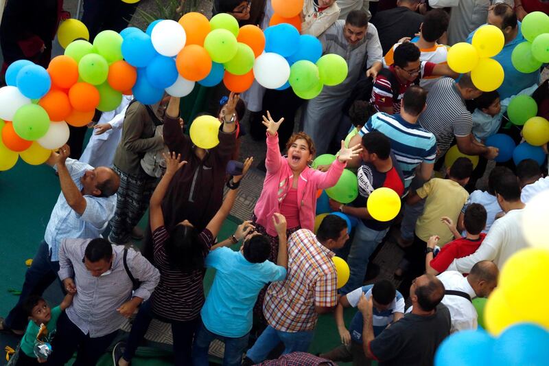 People try to catch balloons after Eid Al Adha prayers outside al-Seddik mosque in Cairo, Egypt. AP