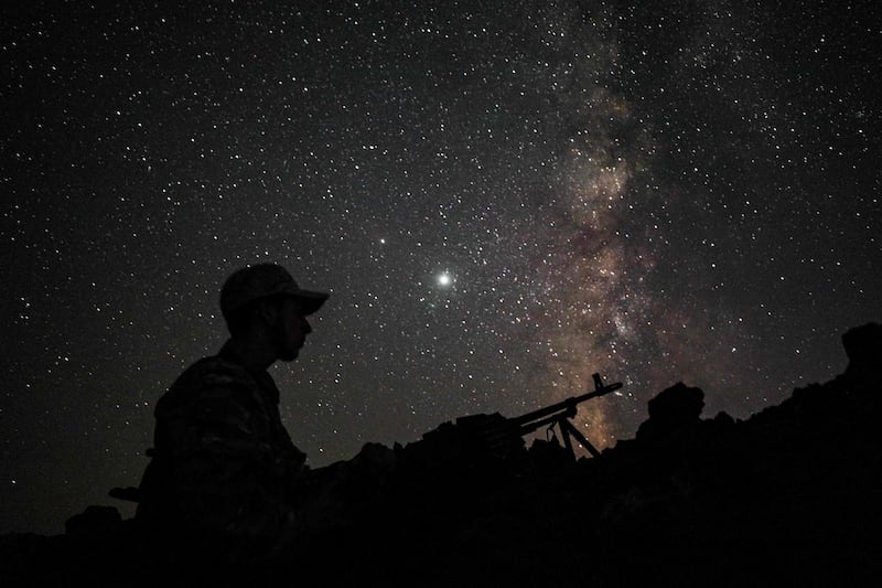 This long-exposure picture taken shows the Milky Way galaxy rising in the sky above a Syrian fighter of the Turkish-backed National Front for Liberation group on watch duty at an outpost in the town of Taftanaz along the frontlines in the country's rebel-held northwestern Idlib province.  AFP