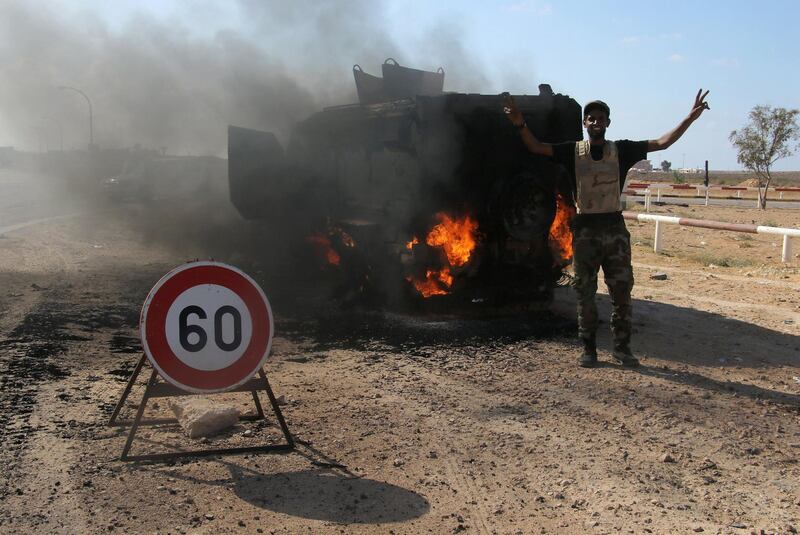 A member of the Libyan National Army flashes a victory sign next to a burning tank after clashes to recover oil ports in Ras Lanuf, Libya June 21, 2018. Picture taken June 21, 2018. REUTERS/Stringer.  NO RESALES. NO ARCHIVE