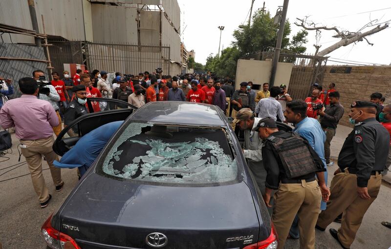 Police officers survey a damaged car at the site of an attack at the Pakistan Stock Exchange entrance in Karachi. REUTERS