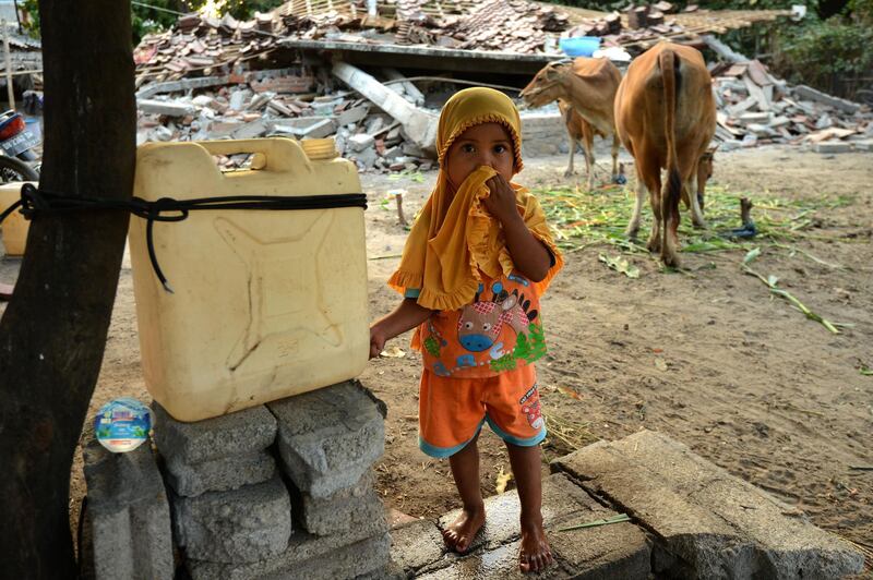 A girl standing in front of her damaged house in Kayangan subdistict in northern Lombok. AFP