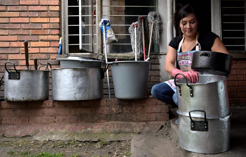 Maria Edilma Aguilar cleans pots as she works as a maid, in Bogota on February 14, 2021. Edilma lost her job in a beauty salon in March, 2020 due to the COVID-19 pandemic, and she had to work as a maid. / AFP / Raul ARBOLEDA

