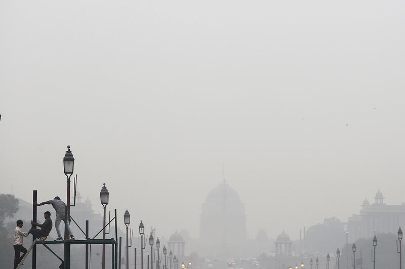 Workers install a closed circuit television camera (CCTV) on King's Way boulevard as the Presidential Residence stands in the distance while shrouded in smog in New Delhi, India. Anindito Mukherje / Bloomberg