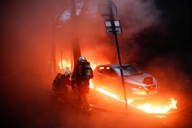 Firefighters work next to a car surrounded by flames during a protest against the "Global Security Bill'', that right groups say would make it a crime to circulate an image of a police officer's face and would infringe journalists' freedom in the country, in Paris, France, December 5, 2020. REUTERS/Gonzalo Fuentes     TPX IMAGES OF THE DAY