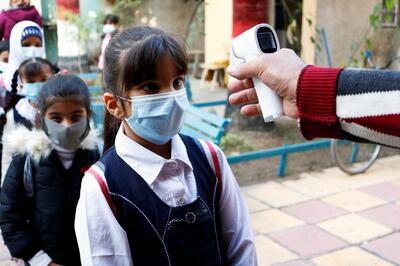 An employee checks a student's temperature following the reopening of their school, after months of closure due to the spread of the coronavirus disease (COVID-19), in Baghdad, Iraq November 29, 2020. REUTERS/Saba Kareem