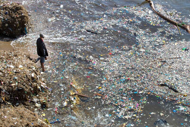 A volunteer looks at a pile of plastic waste and garbage floating on the sea in the Fuerte San Gil beach, during a day of cleaning and environmental recovery in Santo Domingo, Dominican Republic. EPA