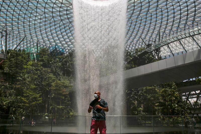 A tourist wearing a protective mask stands near the Rain Vortex at the Jewel Changi Airport mall in Singapore.  EPA