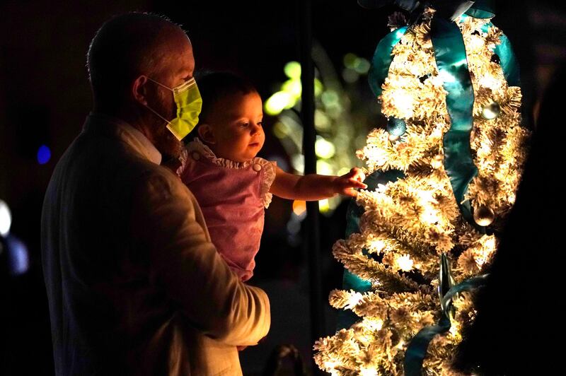 Allan Gubbins and his daughter Helena look at a Christmas tree during an outdoor Christmas Eve Service of Lights at the Granada Presbyterian Church in Coral Gables, Florida. AP Photo