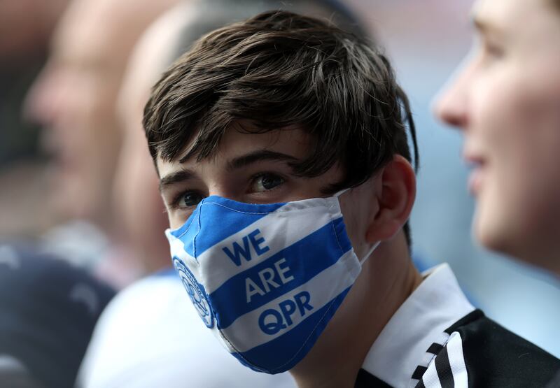 A Queens Park Rangers Fan waring a branded face mask in the stands at the Kiyan Prince Foundation Stadium.