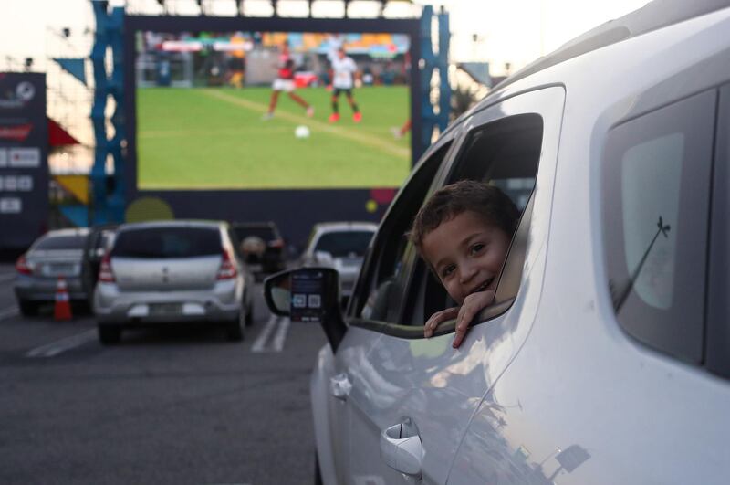 A child looks out of a car window as Flamengo's soccer fans watch the Brasileiro Championship match between Flamengo and Atletico Mineiro from cars during a drive-in show, in Rio de Janeiro, Brazil. Reuters