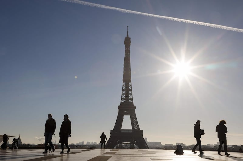 People walk in front of the Eiffel Tower, on the Trocadero plaza in Paris on November 18, 2020, during a second lockdown in France aimed at containing the spread of Covid-19 pandemic, caused by the novel coronavirus. / AFP / Ludovic MARIN
