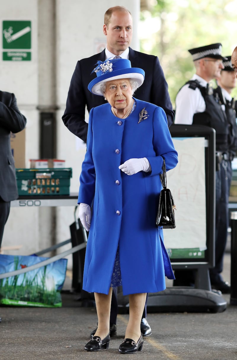 Queen Elizabeth II, in blue, and Prince William, Duke of Cambridge, visit the scene of the Grenfell Tower fire on June 16, 2017, in London. Getty Images