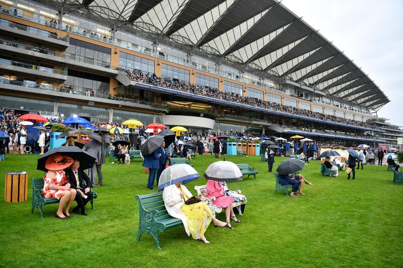 Racegoers shelter under umbrellas as they watch the racing on Day 1 of Royal Ascot. EPA