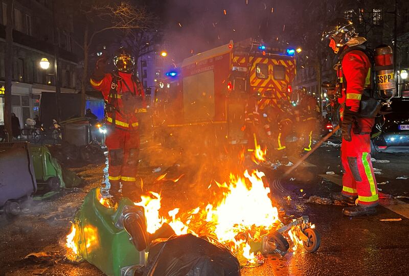 French firefighters extinguish burning rubbish bins. Reuters