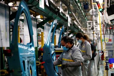 Employees, wearing protective face masks, work on the automobile assembly line of Renault Zoe cars at a factory in Flins. Reuters