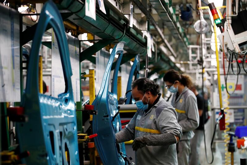 FILE PHOTO: Employees, wearing protective face masks, work on the automobile assembly line of Renault ZOE cars at the Renault automobile factory in Flins as the French carmaker ramps up car production with new security and health measures during the outbreak of the coronavirus disease (COVID-19) in France, May 6, 2020. REUTERS/Gonzalo Fuentes/File Photo