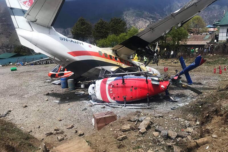 A Summit Air Let L-410 Turbolet aircraft bound for Kathmandu is seen after it hit two helicopters during take off at Lukla airport, the main gateway to the Everest region.  A small plane veered off the runway and hit two helicopters while taking off near Mount Everest on April 14, killing three people and injuring three, officials said.  / AFP / STR
