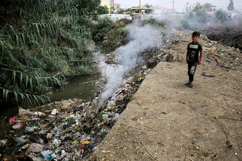 A child stands next to a polluted channel, at a make-shift camp for Syrian refugees in Talhayat, north Lebanon. AFP