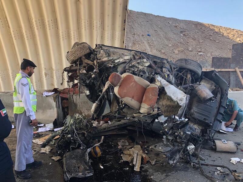 A police officer stands next to the remains of the Emirati driver's vehicle on Tuesday. Courtesy: RAK Police