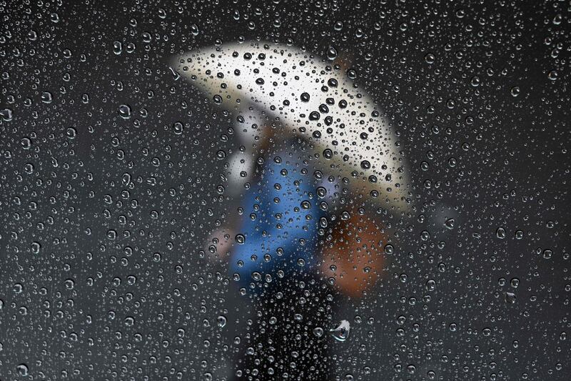 Raindrops are seen on a taxi window while a woman passes by a closed store in Buenos Aires. AFP